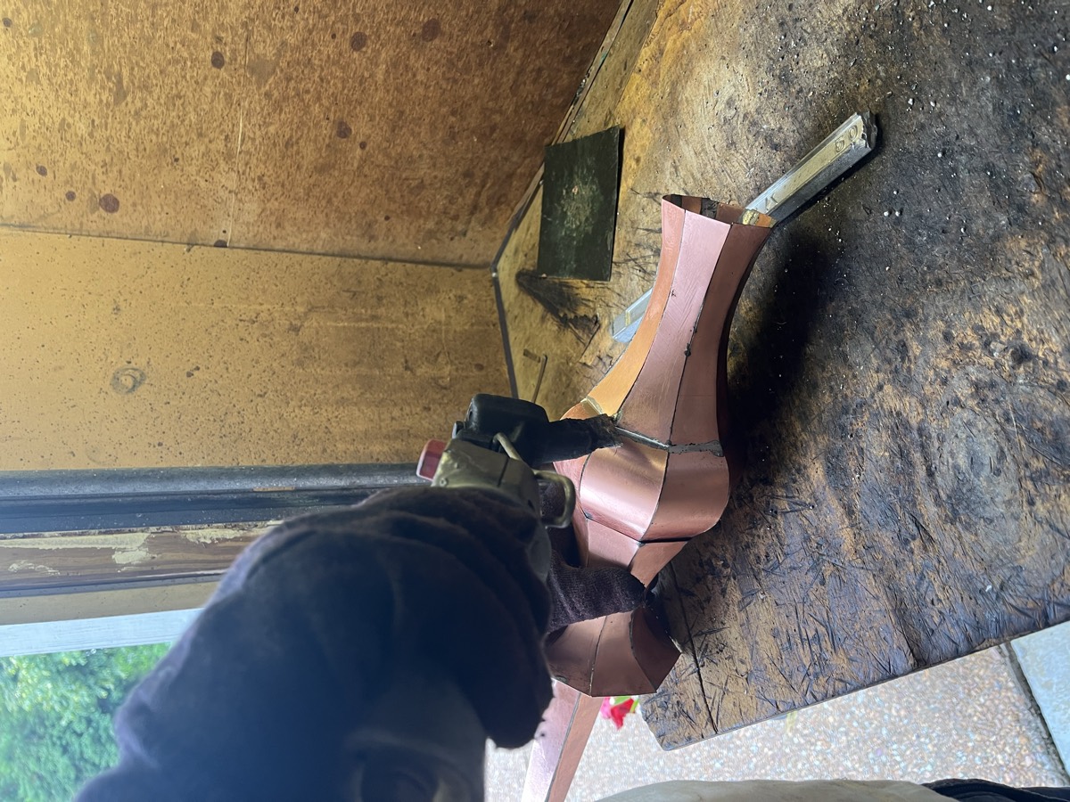 Soldering the seams of a handmade copper finial by hand